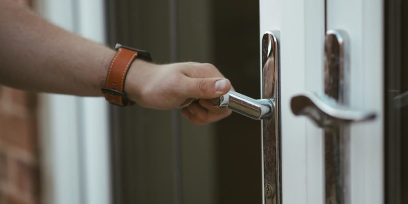 A closeup shot of a person holding a door knob and opening the door