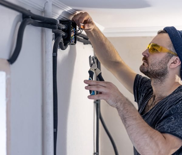 Attractive male electrician repairing an outlet, installing an outlet indoors.