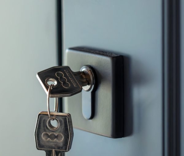Vertical shot with keys in the lock of a blue door and a graphite handle. Cool palette, soft highlights and crisp geometry for a stylish interior.