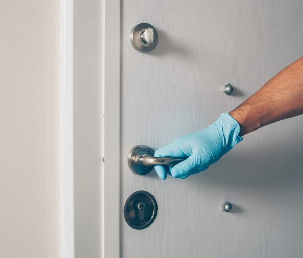 Portrait of a man at room opening the door with hands in gloves coronavirus