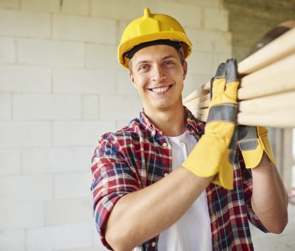Younger carpenter holds wooden planks